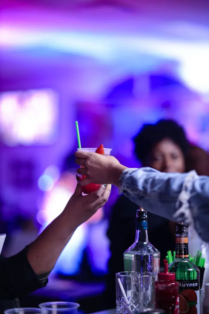 Guests raising their glasses in a toast under purple lights