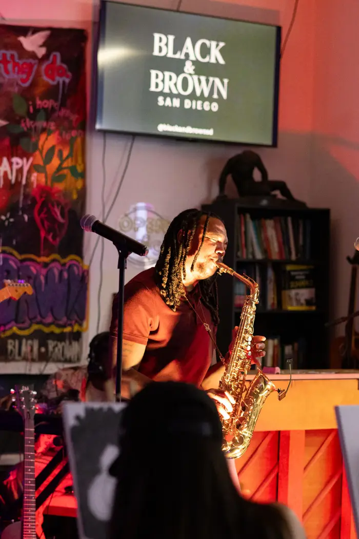 Saxophonist performing under the Black & Brown screen