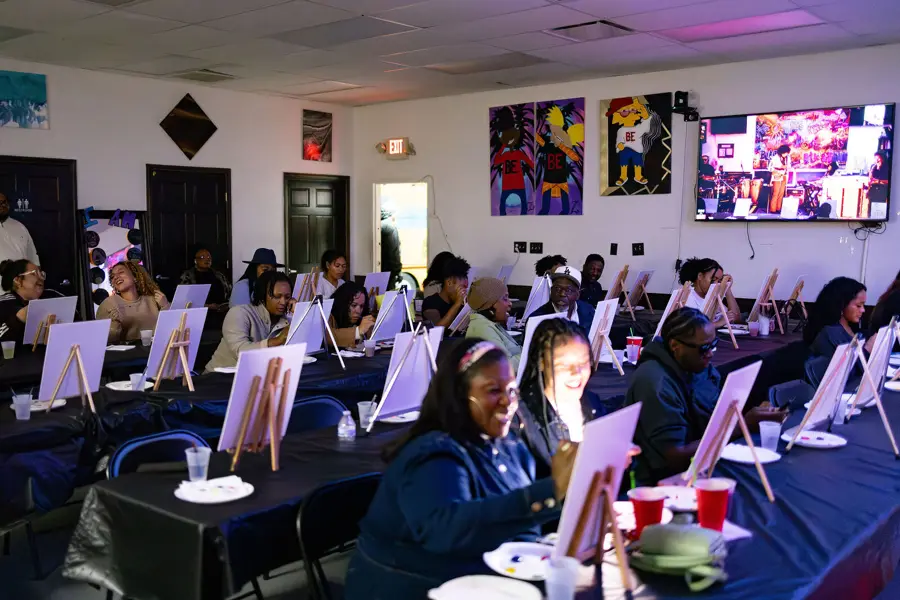 Packed Paint & Sip room with guests at long tables of easels