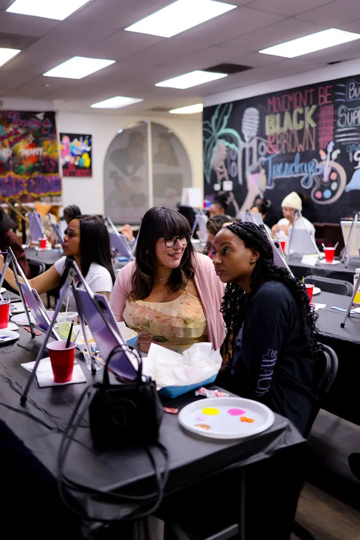 Friends laughing together at a Paint & Sip table