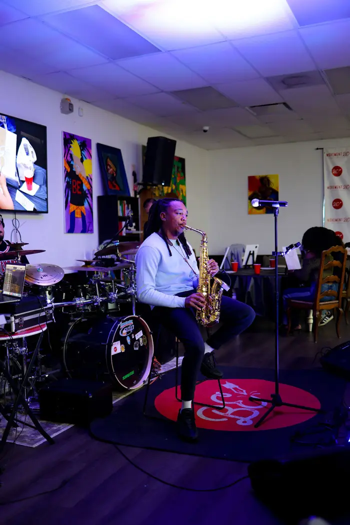 Saxophonist performing beside the drum kit in the painting room