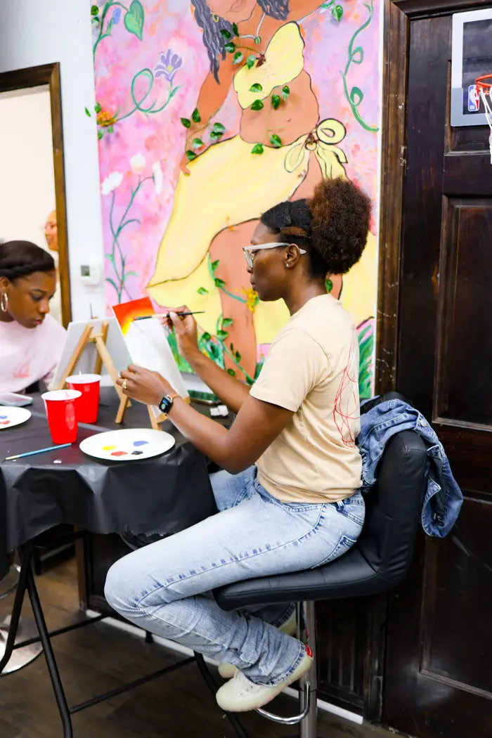 Guest painting beside a colorful mural