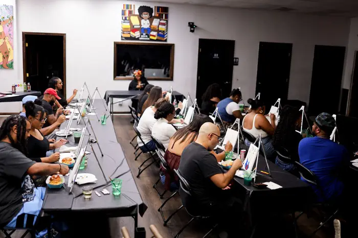Long tables of guests painting in a bright room