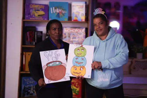 Two guests holding up their finished Halloween paintings